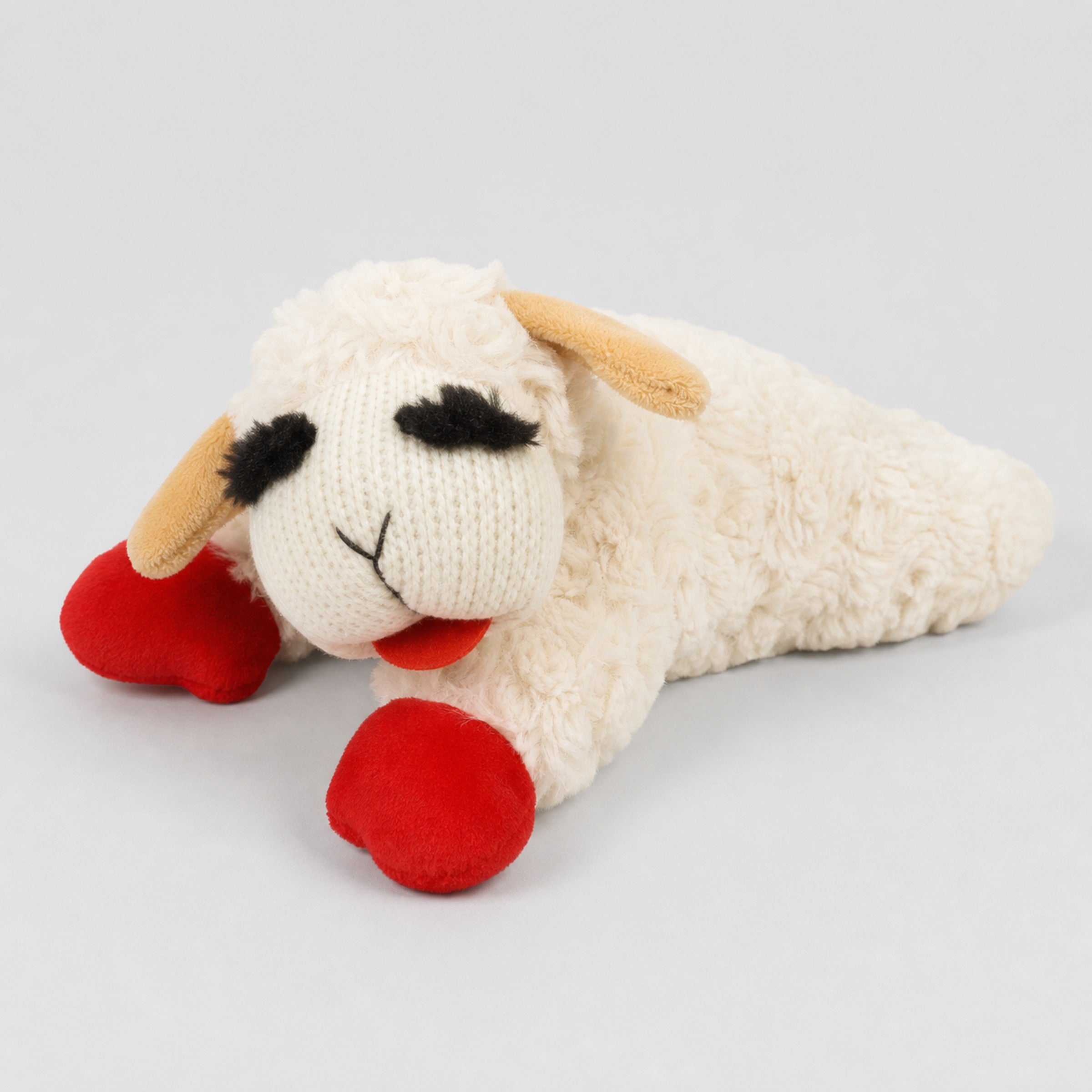 Cream lamb plush dog toy with red feet on light grey studio background